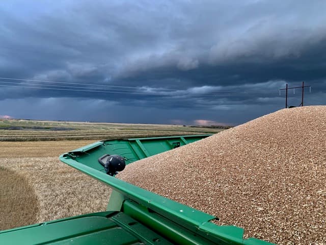 Grain cart under dramatic prairie sky
